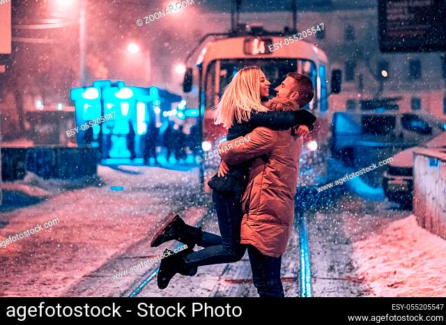 Young adult couple in the arms of each other on the snow-covered tram line