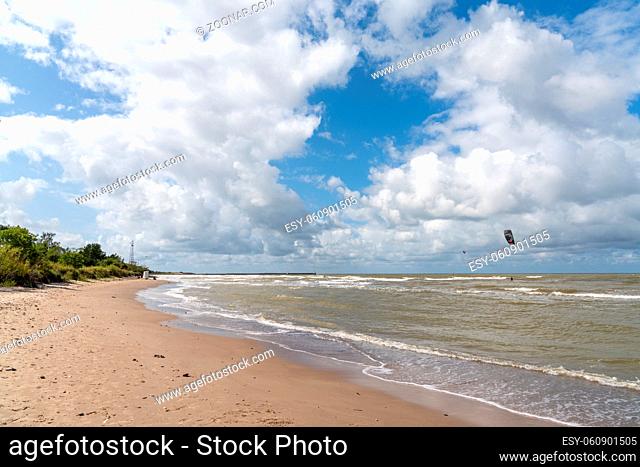 An empty sandy beach and single kite surfer in the Baltic Sea near Pavilosta in Latvia