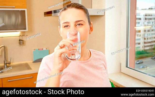 Portrait of beautiful smiling woman drinking water on kitchen before breakfast. Healthy nutrition and lifestyle