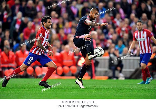 Munich's Arturo Vidal (C) and Madrid's Augusto Fernandez vie for the ball during the Champions League semi-final match between Atletico Madrid and Bayern Munich...