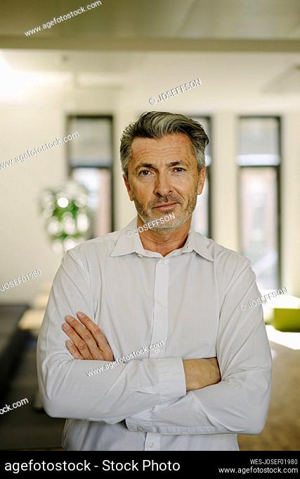 Confident businessman with arms crossed standing at office