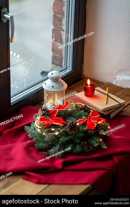 christmas wreath, books, candle, lantern on window