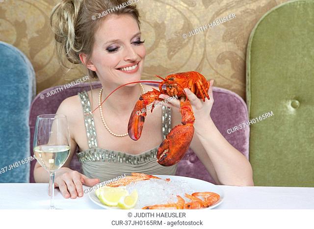 Woman holding lobster in restaurant