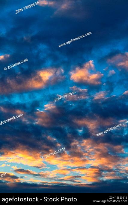 Beautiful clouds in blue sky, illuminated by rays of sun at colorful sunset to change weather. Soft focus, motion blur abstract meteorology background