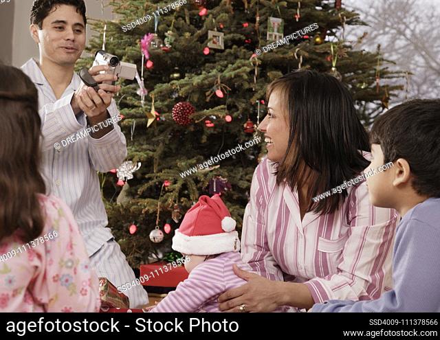 Hispanic father video recording family on Christmas
