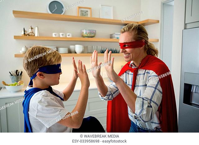 Mother and son pretending to be superhero in the kitchen