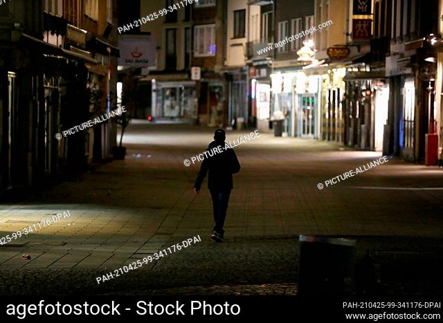 24 April 2021, North Rhine-Westphalia, Duesseldorf: A person walks through an empty street in Düsseldorf's old town. Since 24 April