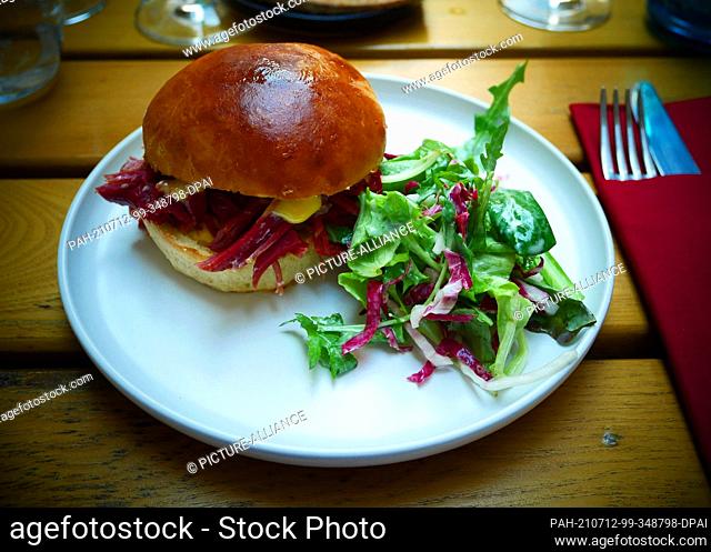 04 July 2021, Berlin: Salt beef burger in brioche with Dijon mustard mayo, cucumber relish and vinegar shallots, taken at the wine bar Weinlobby in Berlin...