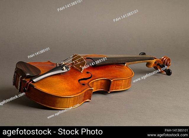 An old violin with slight scratches and damage lying on a neutral, gray background. | usage worldwide. - /Deutschland