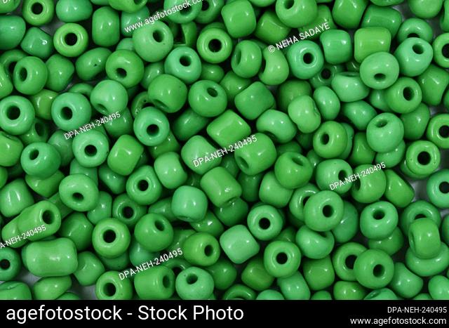 Green Beads on the white background. Background or texture of beads. Close up, macro, It is used in finishing fashion clothes