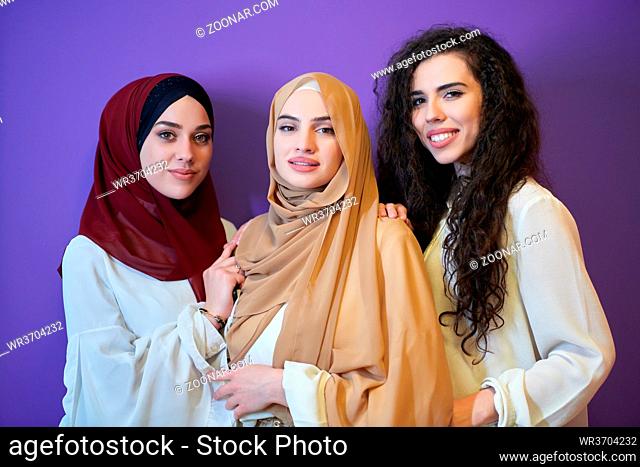 Young muslim women posing on purple background. Happy and pretty girls two wearing hijab representing Ramadan concept