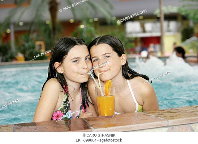 Two girls drinking juice in a pool, Bad Waltersdorf, Styria, Austria