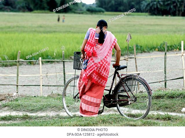 Woman standing near cycle ; Bongaigaon ; Assam ; India