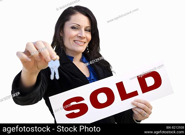 Smiling hispanic woman holding sold real estate sign and keys isolated on white