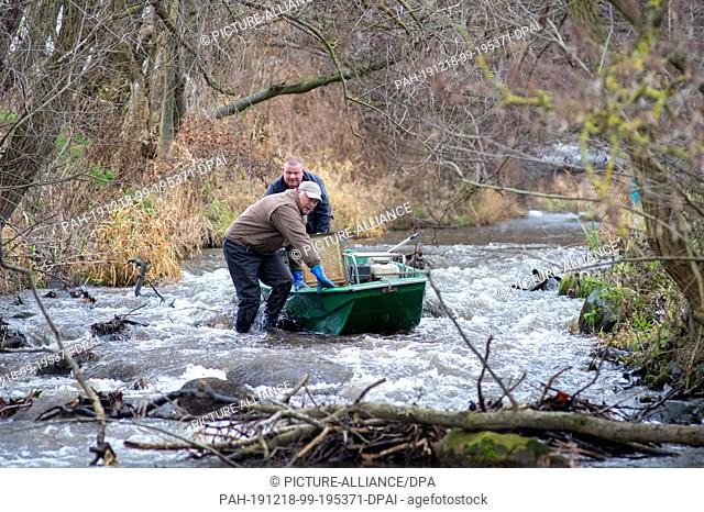 18 December 2019, Saxony-Anhalt, Zerbst: Jens Windheuser (l) and Robert Frenzel from the Institute for Inland Fisheries in Potsdam push their boat in the groove...