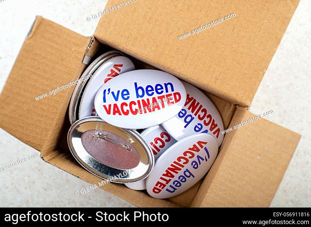 Vaccination campaign button pins in carton box on light tabletop flat lay view