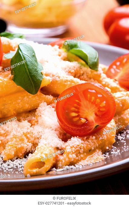 penne with tomato basil and cheese in brown plate on wooden table