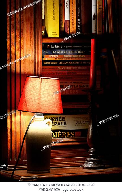 bookcase with many books about famous Great Belgian beers, Grandes Bieres de Belgique, still life scene with books about beers, lamp and candlestick