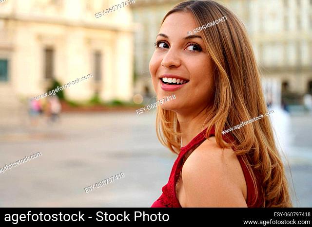 Smart interested young woman turn the head while walking against urban background
