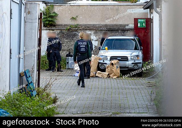 20 September 2023, North Rhine-Westphalia, Duisburg: Police officers stand in a backyard in downtown Duisburg, with paper bags of evidence on the ground