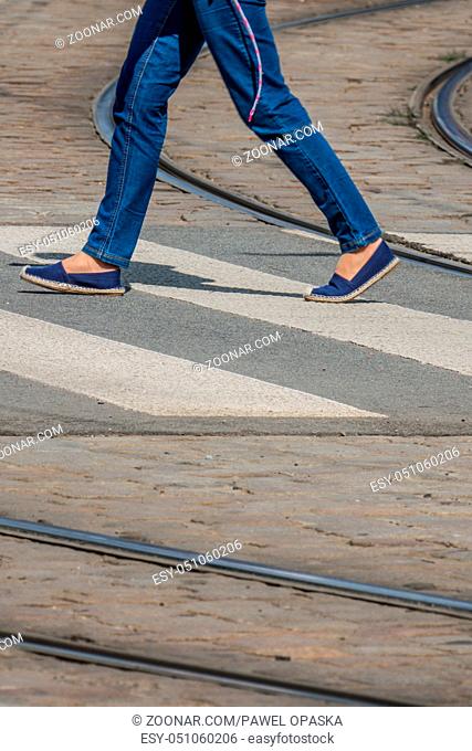 Woman in jeans crossing the road in town in summer