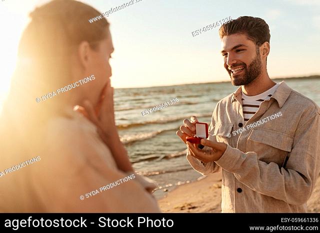 man with ring making proposal to woman on beach
