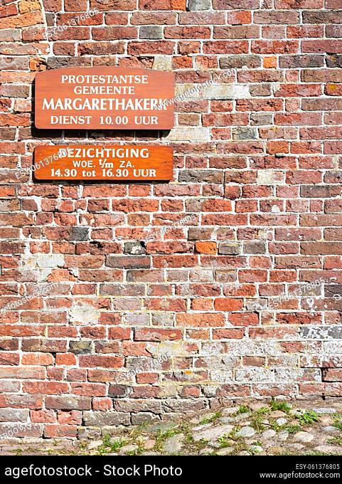 Norg, Drenthe, The Netherlands - Brick stone facade of the Margaretha church with inscription of timeshedule for visitation and cult service