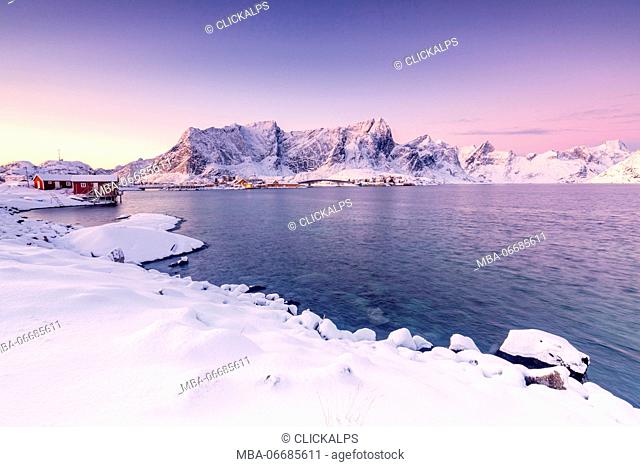 The colors of dawn frames the fishermen houses surrounded by frozen sea Reine Bay Nordland Lofoten Islands Norway Europe