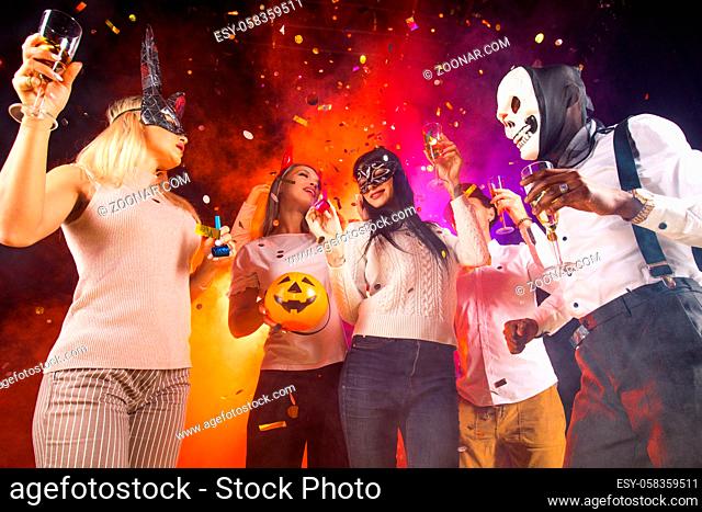 Happy people men and women mixed race dancing together on Halloween party
