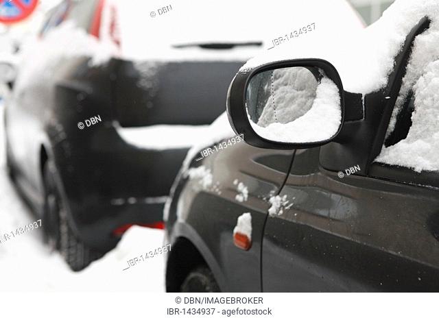 Left side mirror of a snow-covered black car, winter, Germany