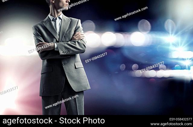 Businessman with arms crossed on chest standing in lights of stage