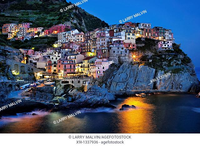 Manarola view at dusk across harbor with light reflection on water