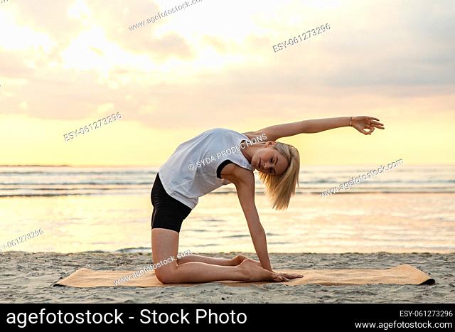 woman doing yoga camel pose on beach