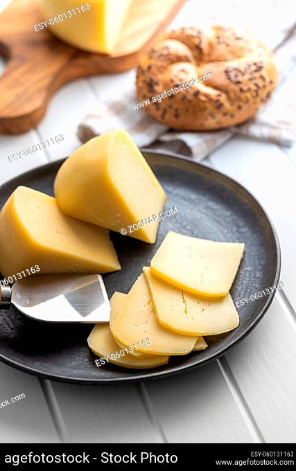 Block of hard cheese. Sliced cheese on plate