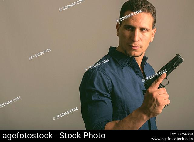 Studio shot of young muscular Persian businessman against gray background