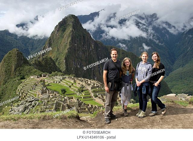 Man with his family with The Lost City of The Incas in the background, Machu Picchu, Cusco Region, Peru