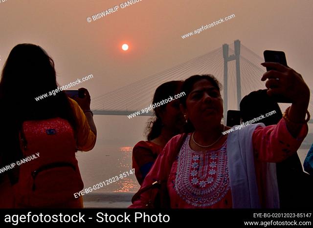 Dec 31, 2022, Kolkata, India. A person takes a selfie during the sunset across the  Howrah Bridge (Vidyasagar Setu) On River Ganges