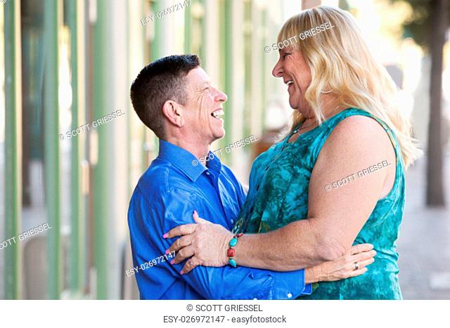 Middle aged adult transgender couple embracing outside in urban setting