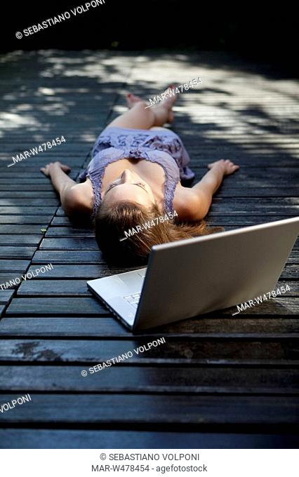 una donna sdraiata in una terrazza con un computer