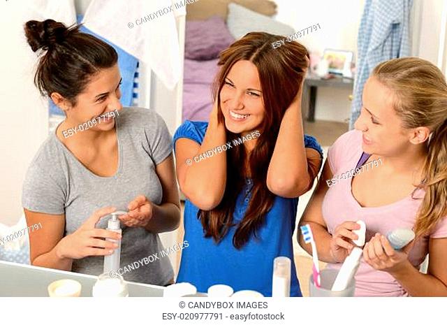 Three laughing teenager girls talking in bathroom