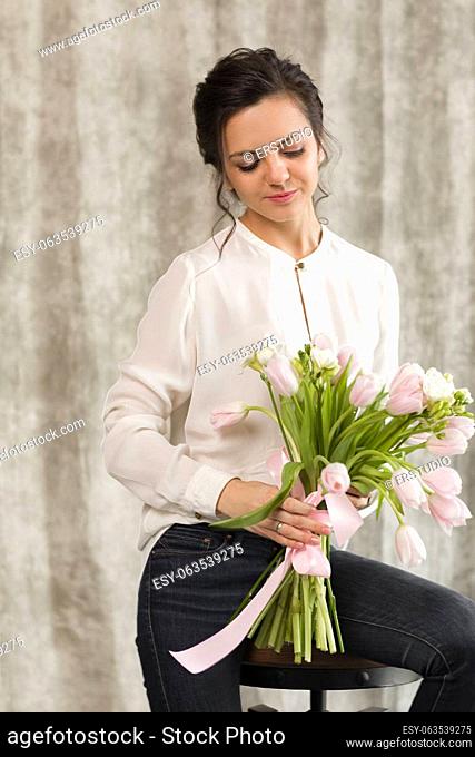 portrait of a beautiful brunette woman with a bouquet of tulips flowers
