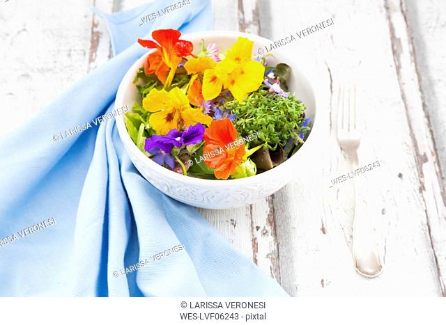 Bowl of leaf salad with various edible flowers
