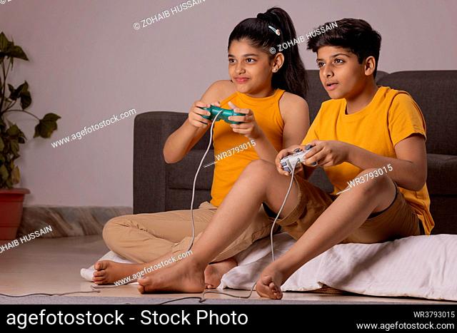 Boy and girl playing video games in living room at home