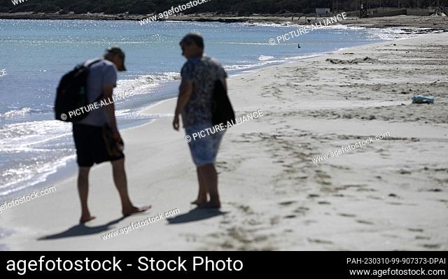 10 March 2023, Spain, Son Servera: A couple walks on the beach of Cala Millor in Mallorca. Unusually high temperatures for this time of year are expected this...