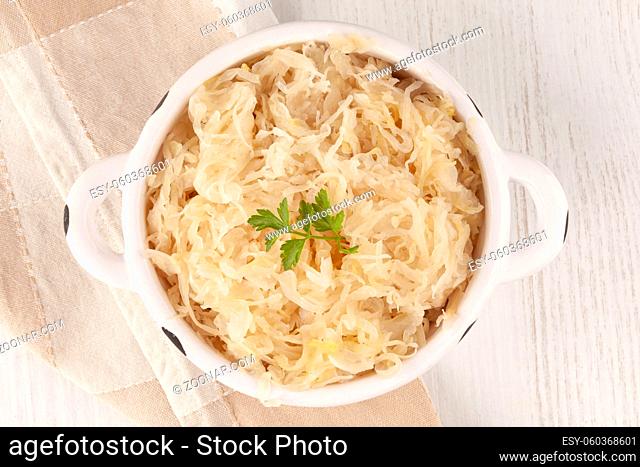 Bowl of sauerkraut on white wooden table from above. Sour cabbage top view