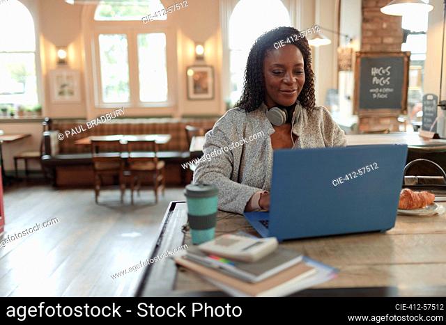 Woman working at laptop on table in cafe