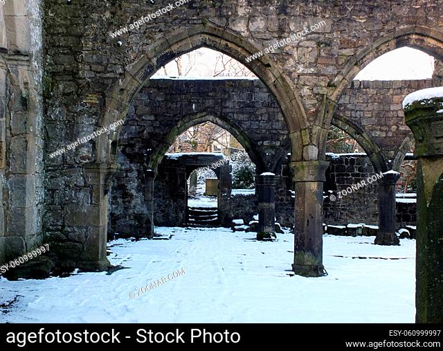 arches and columns in the ruined medieval church in hebden bridge west yorkshire with snow covering the ground in winter