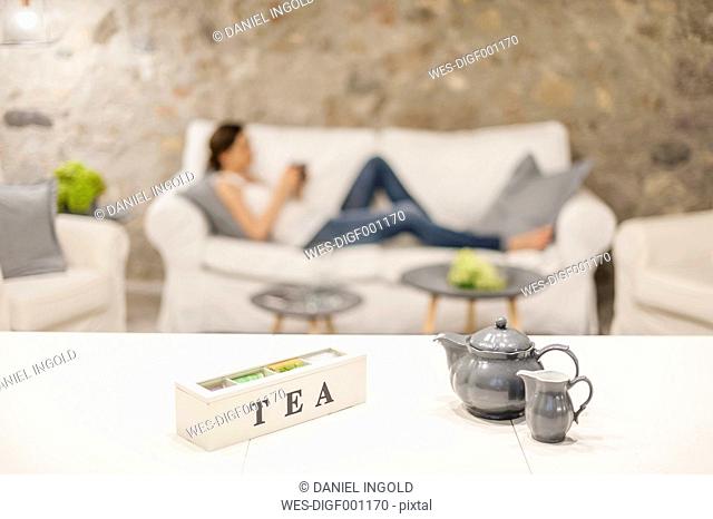 Woman sitting on couch, drinking tea