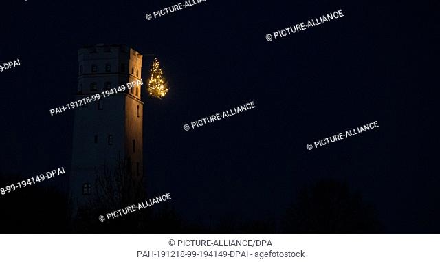 18 December 2019, Bavaria, Biberbach: In the district of Markt there is a Christmas tree hanging from the castle tower at a lofty height