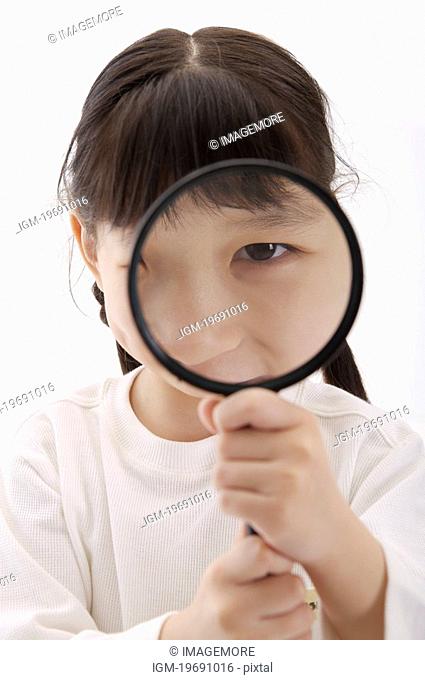 Girl holding magnifying glass to her face